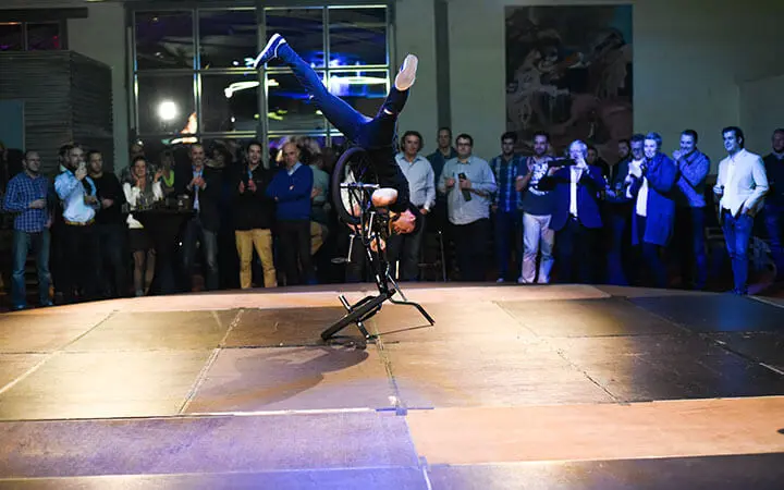 Ein Breakdancer im Rollstuhl balanciert kopfüber auf einer Hand in der Mitte der Bühne, während die Menge zuschaut und applaudiert.