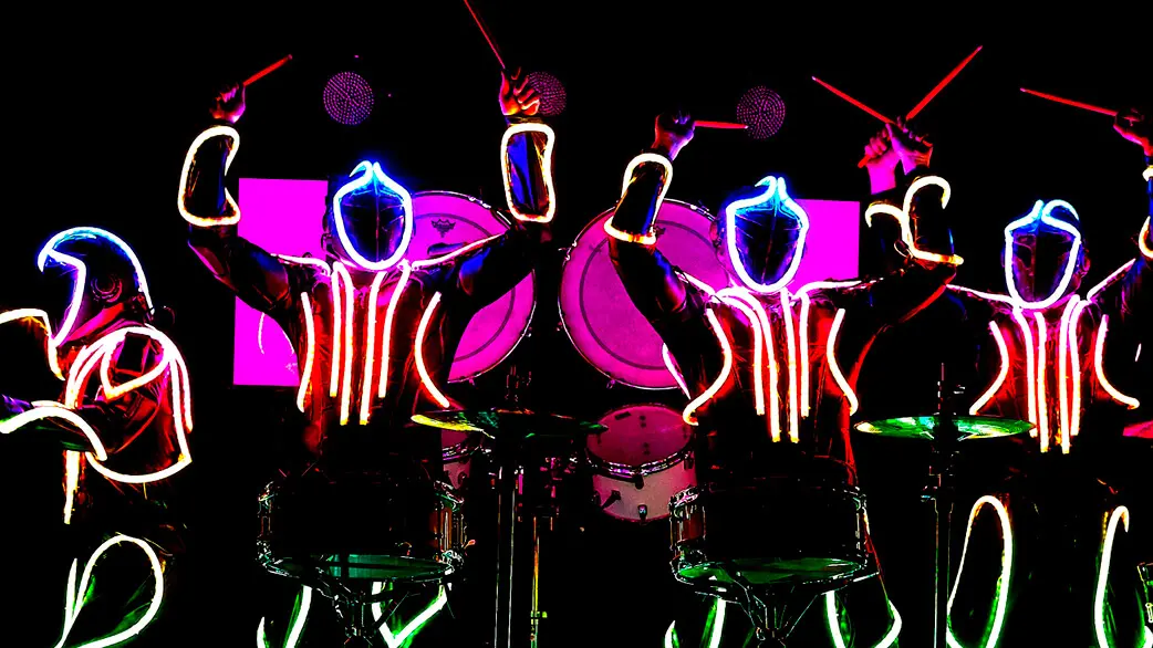 Trommler in leuchtenden LED-Anzügen, futuristisch und dynamisch inszeniert